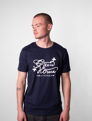 Man wearing a navy blue Green House t-shirt with white text and graphics on a plain background