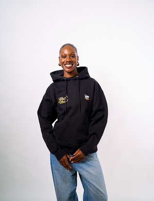 Person wearing a black Green House X Patta hoodie with logos on a white background
