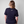 Person wearing a navy blue t-shirt with a Green House logo on the back against a plain background