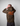 Person wearing aGreen House camouflage hoodie with orange text on the back against a gray background