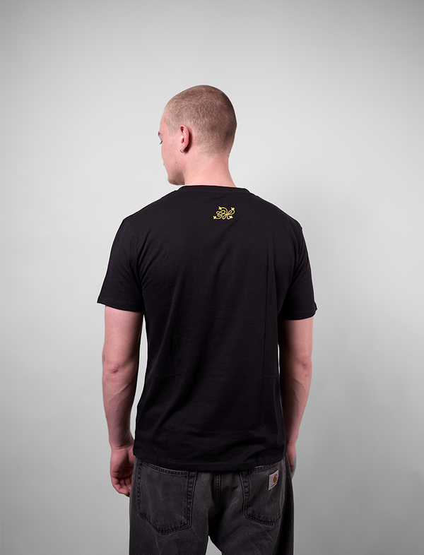 Man wearing a black t-shirt with a Greenhouse logo on the back against a plain background