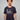 Man wearing a navy blue Green House Feeding t-shirt with a logo and text on a gray background