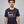 Man wearing a navy blue Green House Feeding t-shirt with a logo and text on a gray background