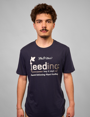 Man wearing a navy blue Green House Feeding t-shirt with a logo and text on a gray background