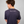 Person wearing a navy blue Green House Feeding t-shirt with 'keep it simple!' text on the back against a gray background