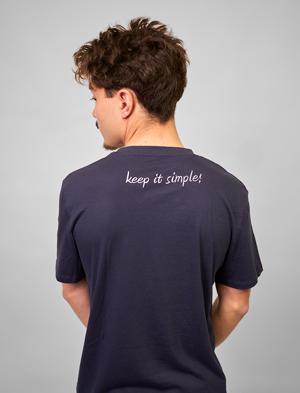 Person wearing a navy blue Green House Feeding t-shirt with 'keep it simple!' text on the back against a gray background