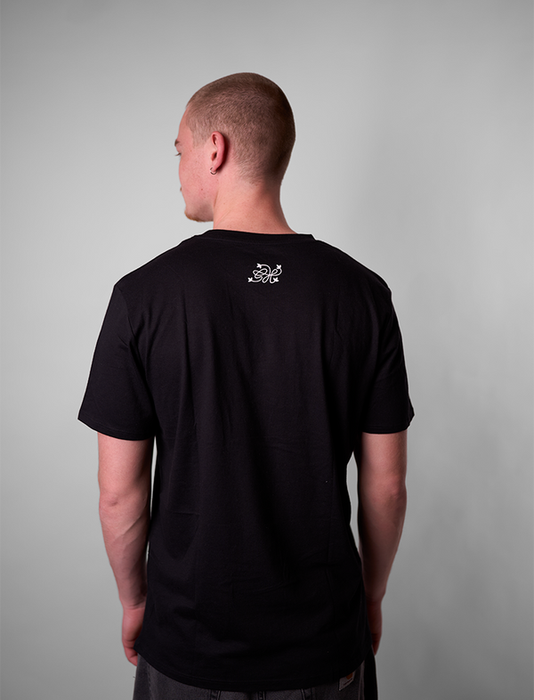 Person wearing a black t-shirt with a greehouse logo on the back against a gray background
